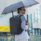 Homme sous un parapluie avec le sac à dos de voyage noir
